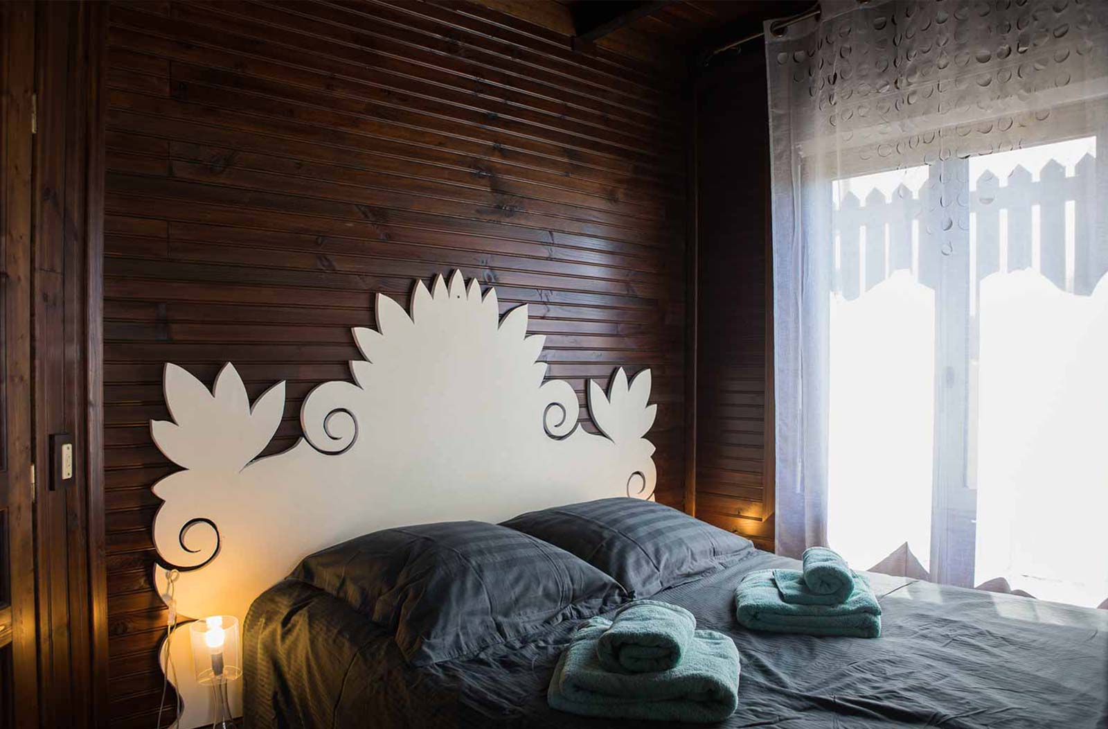 Photo d'une chambre avec lit double, les murs sont en bois et il y a une porte fenêtre.
