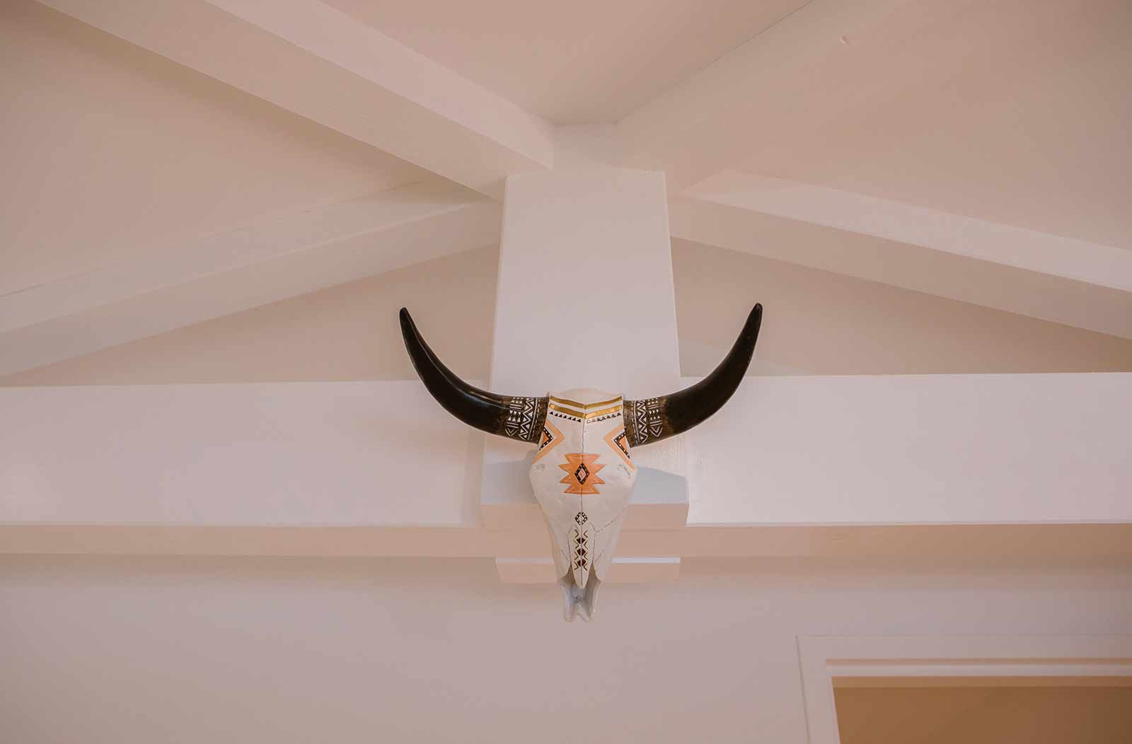 Photo d'un faux crâne de bison décoré et peint accroché sur une poutre.
